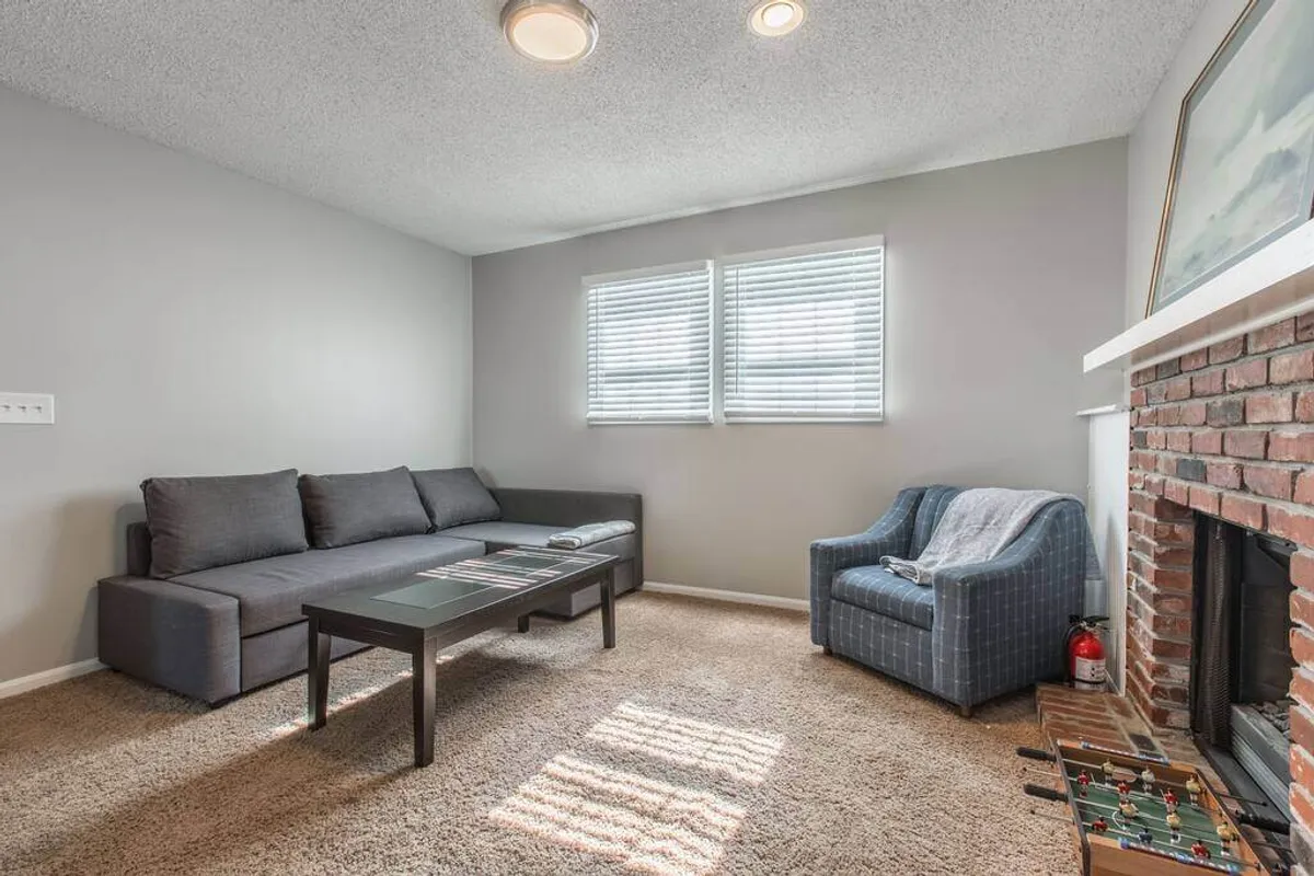 A cozy living area with a plush sofa, coffee table, armchair, and a softly glowing fireplace, perfect for casual conversations, storytelling, or relaxing after a night out.