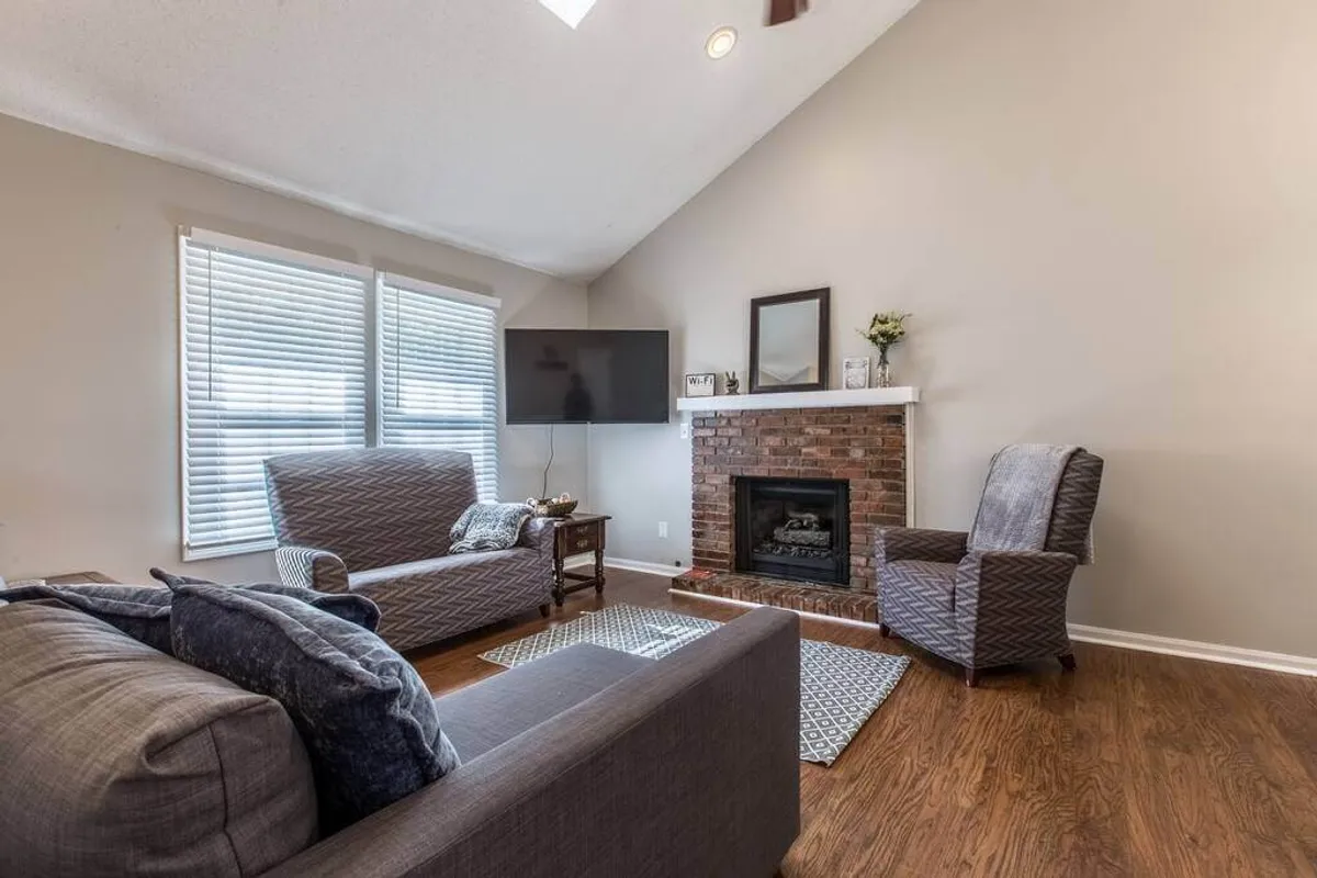 This inviting interior scene highlights a comfortable seating arrangement centered around a fireplace and television. The space is designed for relaxation and socializing, featuring plush chairs and a warm ambiance that encourages both productivity breaks and cozy downtime.