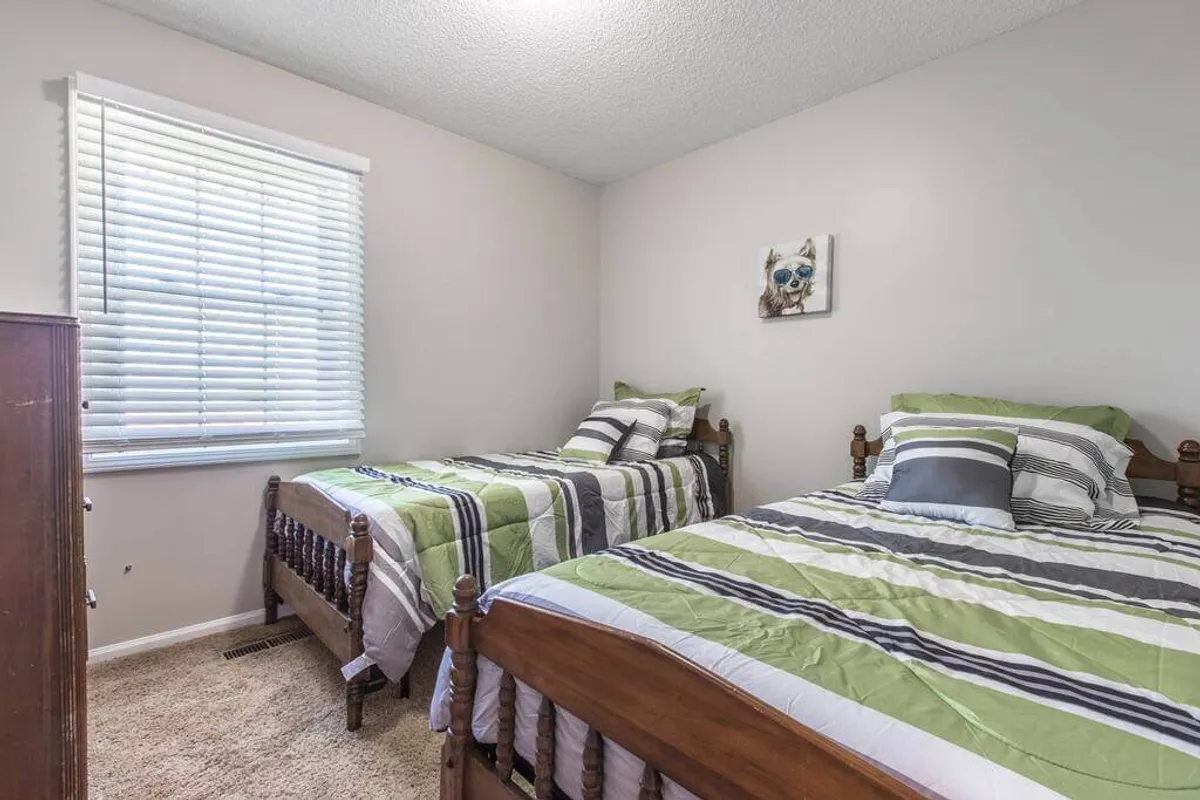 A cheerful bedroom with two twin beds, striped bedding, and decorative wall art. The room offers a comfortable, inviting space perfect for quiet rest, reading, or even a restorative afternoon nap.