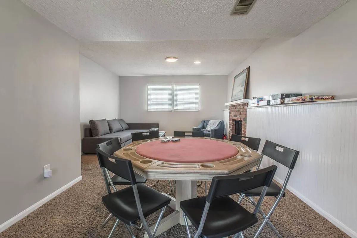 A welcoming space featuring a poker table with friends gathered around, adjacent to a comfortable sofa seating area and a fireplace, suggesting an atmosphere ideal for socializing, celebrating, and enjoying group activities.