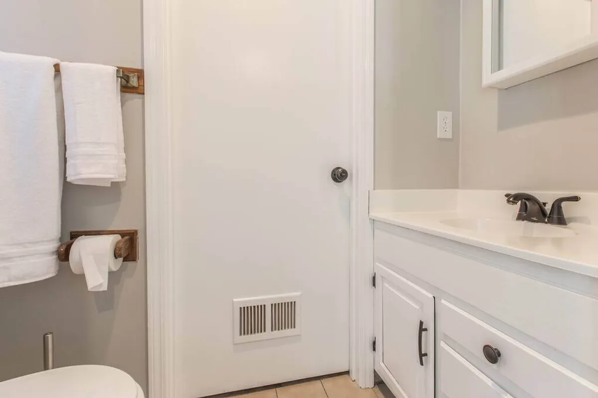 A close-up view of a bathroom sink area adorned with plush white towels and a closed door in the background. The setup suggests a tranquil, spa-like atmosphere perfect for unwinding after a long day.